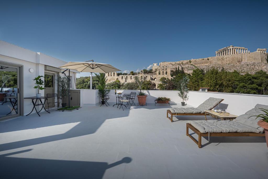 a patio with couches and tables and a view of the city at Acropolis and Odeon Panorama in Athens