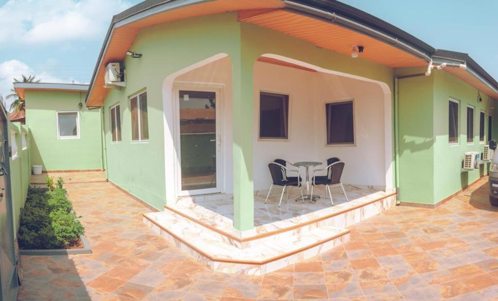una casa con una mesa y sillas en un patio en Emron Homelodge en Accra