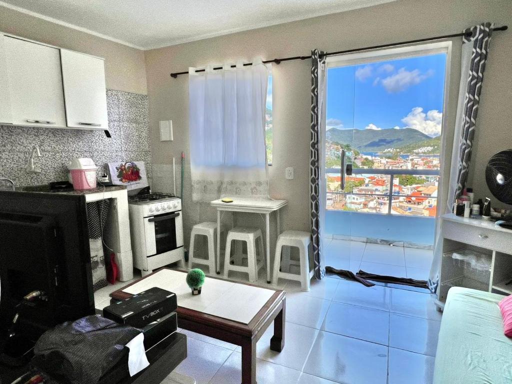 a kitchen and living room with a view of a city at Quitieenete Arraial do Cabo in Arraial do Cabo