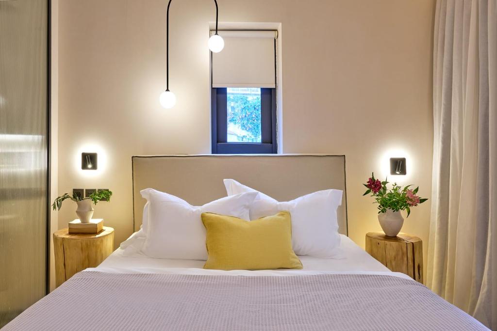 a bedroom with a bed with white sheets and yellow pillows at Skiathos Senses in Skiathos
