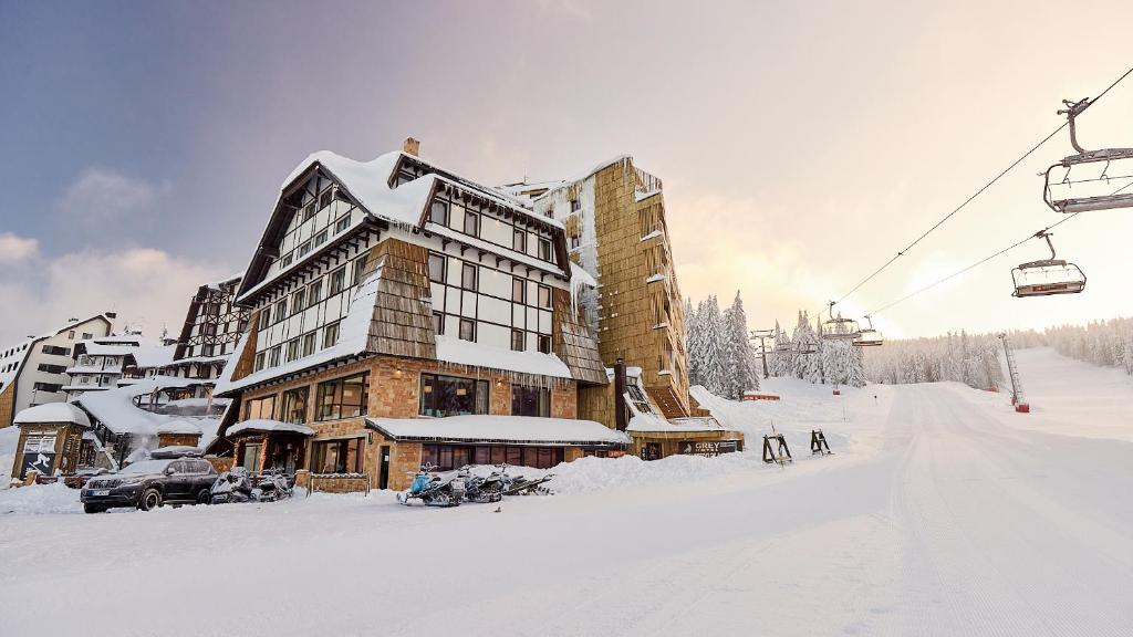 eine Skihütte im Schnee neben einem Skilift in der Unterkunft Grey Family Hotel in Kopaonik