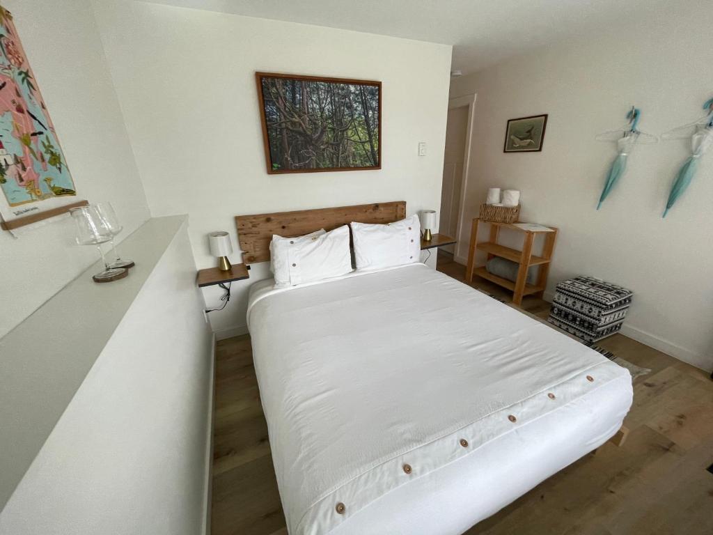 1 dormitorio con 1 cama grande con sábanas blancas en Sounds of the Sea, en Ucluelet