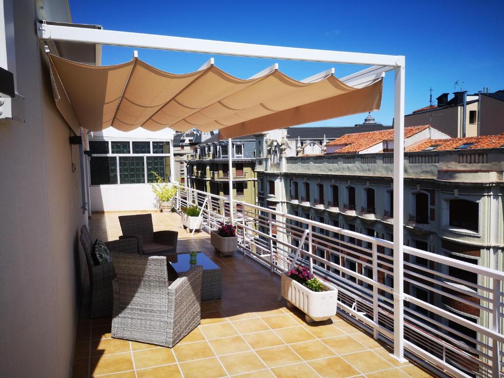 un balcón con una sombrilla grande en un edificio en BURGO NUEVO Ático de lujo en pleno centro con terraza y vistas - leonapartamentos, en León