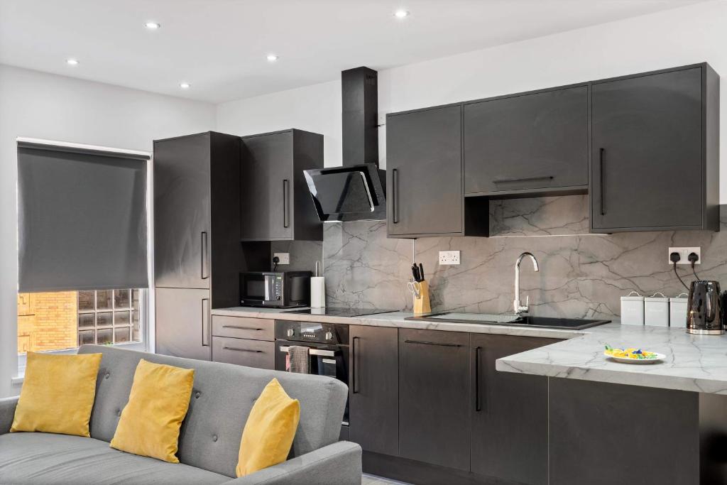 a kitchen with gray cabinets and a couch in a room at Cowgate Luxury Apartments in Peterborough