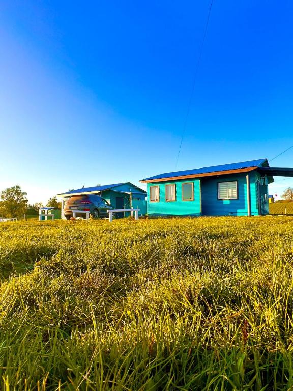 a blue house in the middle of a grass field at Cabañas Alto las Torres in Los Ángeles