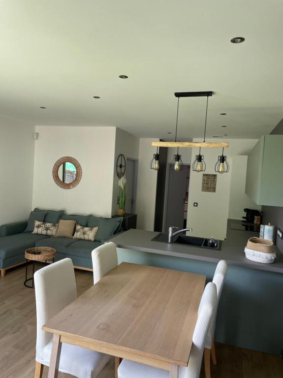 eine Küche und ein Wohnzimmer mit einem Tisch und einem Sofa in der Unterkunft Appartement Cocooning entre lacs et montagnes in Saint-Alban