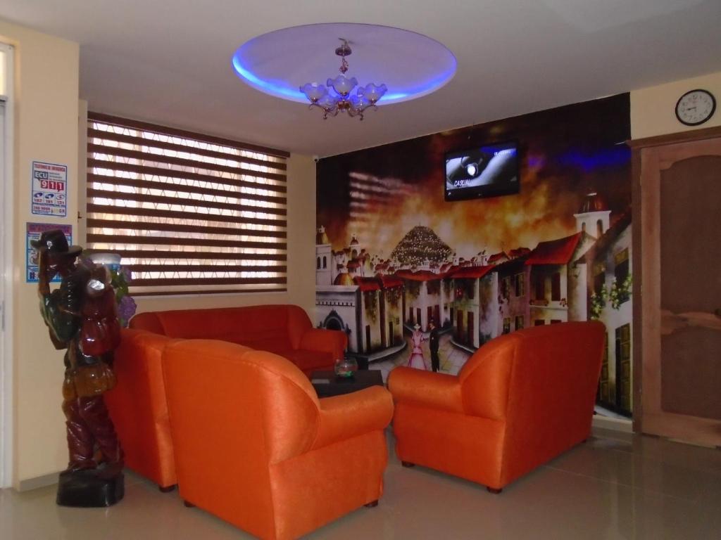 a waiting room with orange chairs and a tv at Hotel El Ejido in Quito