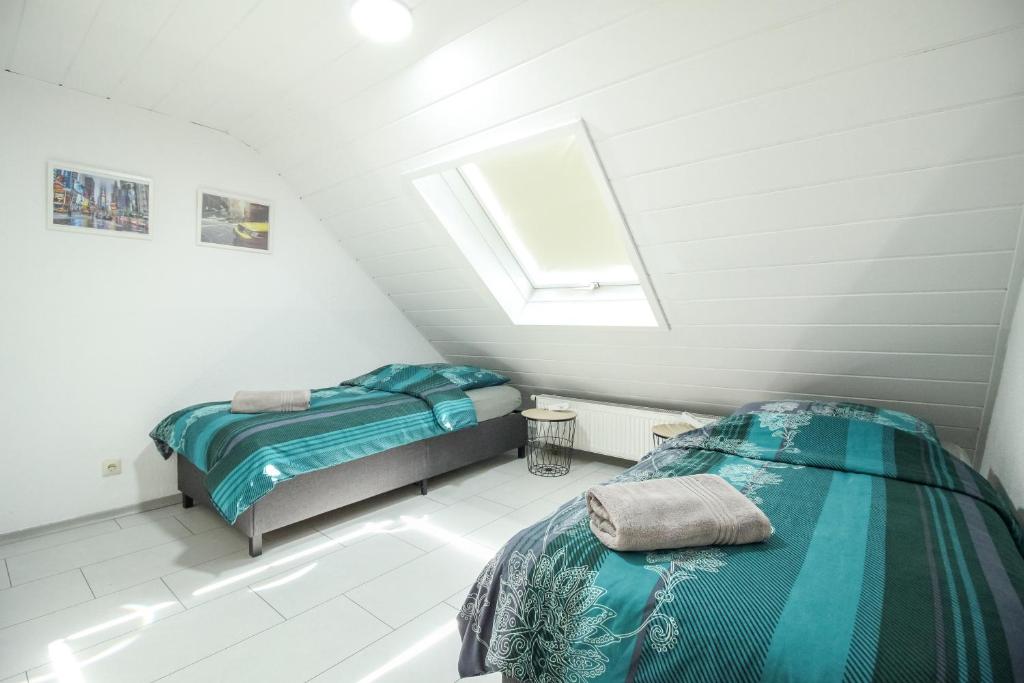 a attic bedroom with two beds and a window at nJoy! Modern & Zentral - WLAN - Badewanne - perfekt für Work & Travel in Göppingen