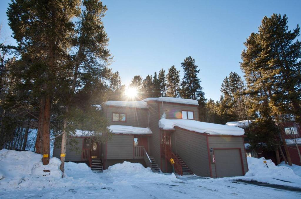 a house in the snow with the sun behind it at Cozy Townhouse on the main bus line in Breckenridge