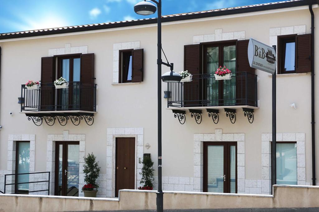 - un bâtiment blanc avec un balcon et un éclairage de rue dans l'établissement Le Suite Di Via Veneto, à Favara