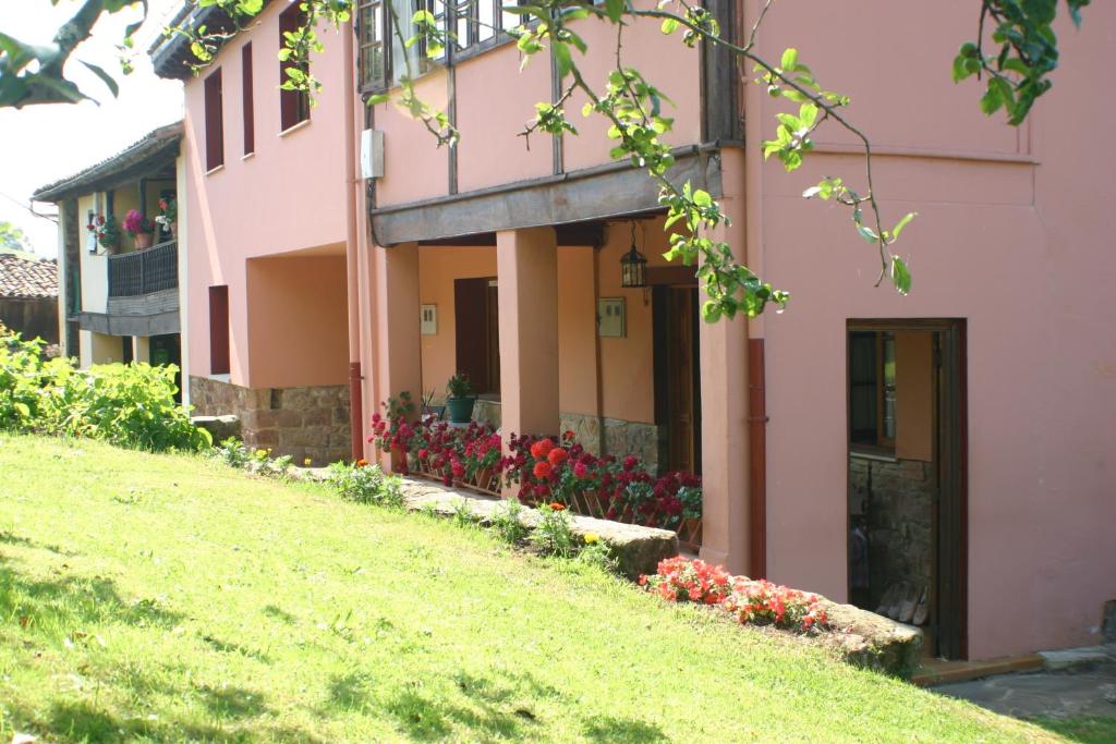 un edificio rosa con flores a un lado. en Fonte San Pedrín en Cajide