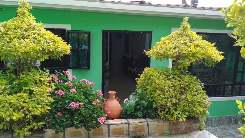 a green house with flowers and a vase in front of it at Casa Shalom R.G. in Paipa