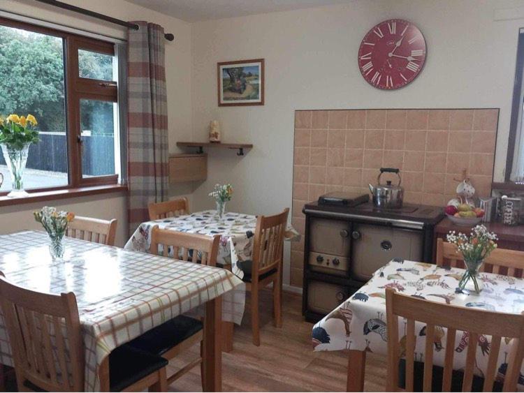eine Küche mit zwei Tischen und einer Uhr an der Wand in der Unterkunft Drumgauty Cottage in Strabane