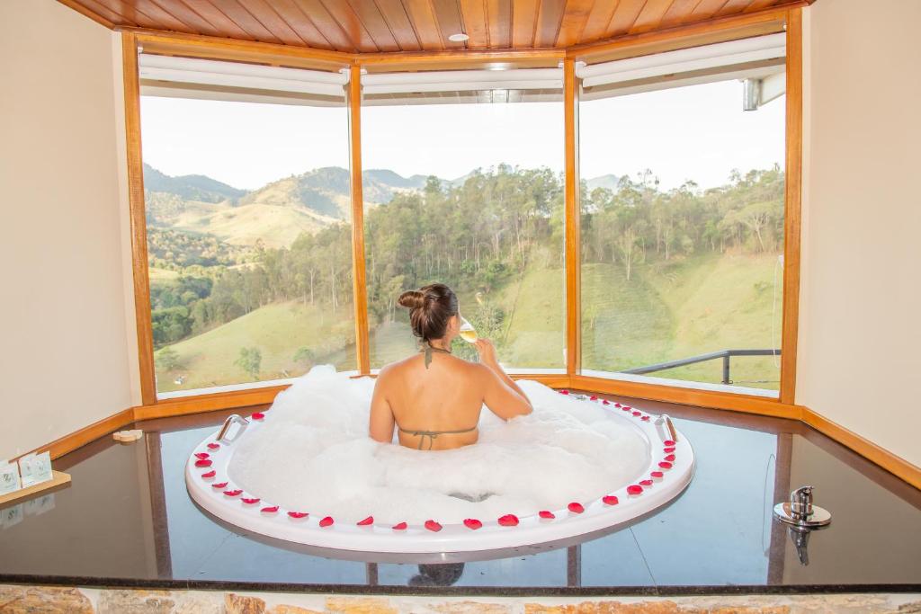 a woman sitting in a round bath tub in a room with a window at Chalé Pedra Madeira in São Bento do Sapucaí