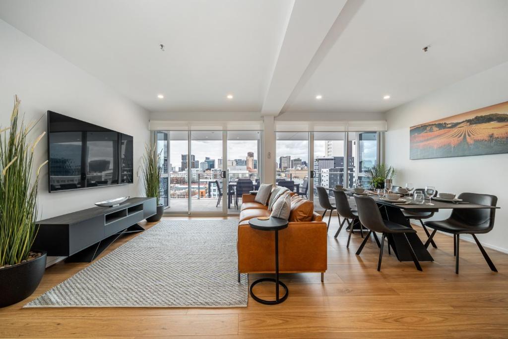 a living room with a couch and a dining room at Ignite at Park Terrace - Elevated City Living in Adelaide