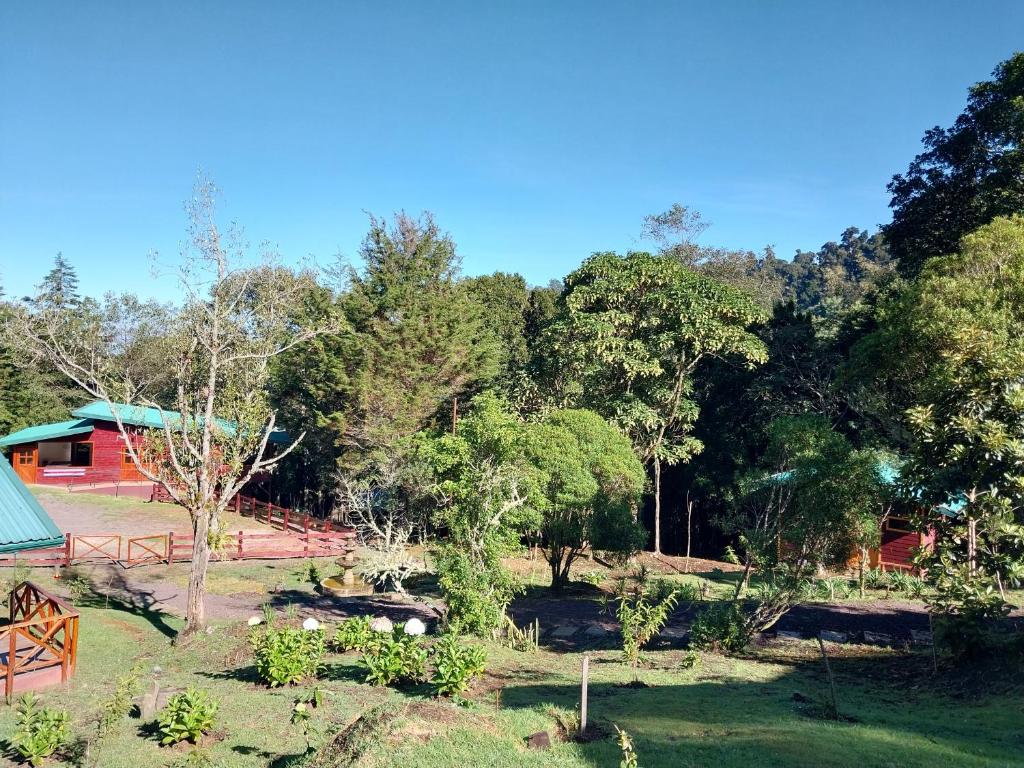 a garden with a red building and trees in the background at Curuba Lodge in El Copey