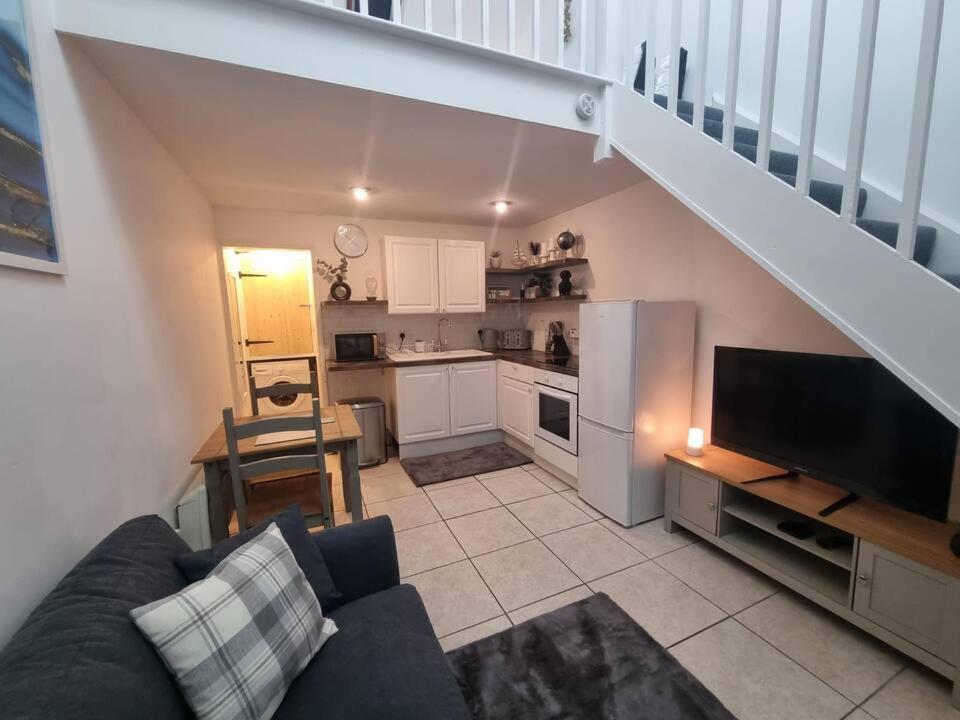 a living room with a couch and a kitchen at Cosy Moat House Cottage #6 in Pembroke