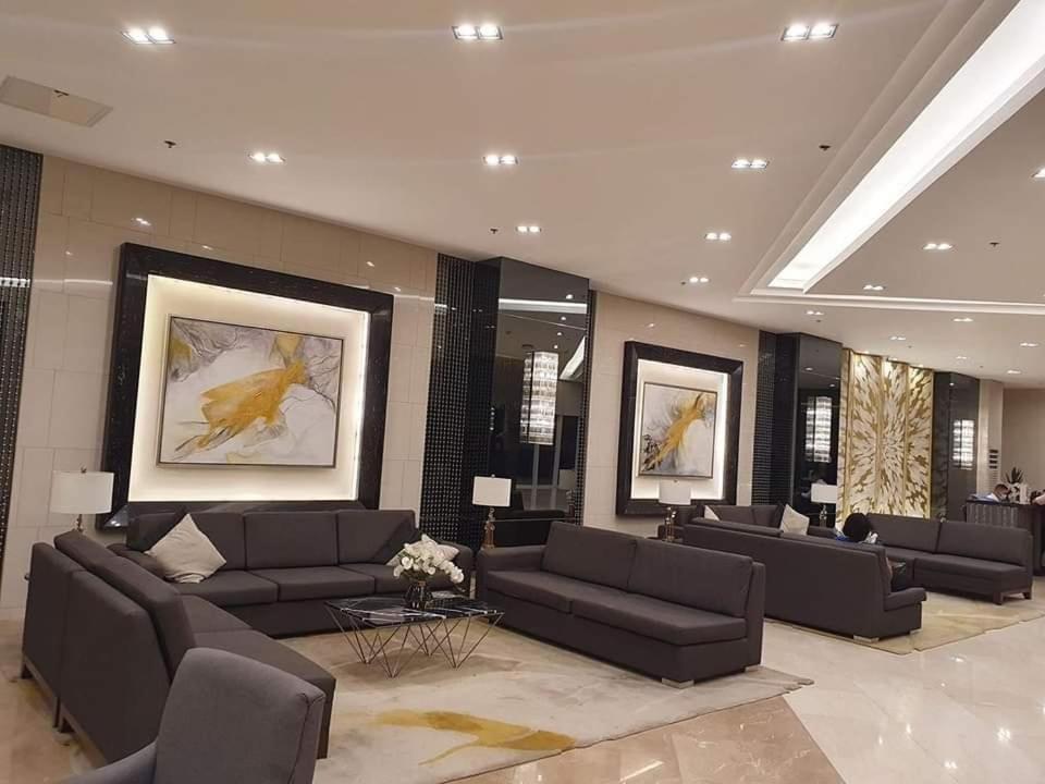 a large lobby with couches and tables and paintings at HOMESNAP CONDOTEL FAME RESIDENCE MANDALUYONG in Manila