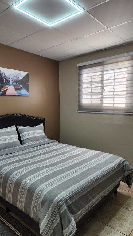 a bedroom with a large bed with a striped blanket at The Layover - 6 mins from the airport, Fully equipped for short and long stays in Kelly Village