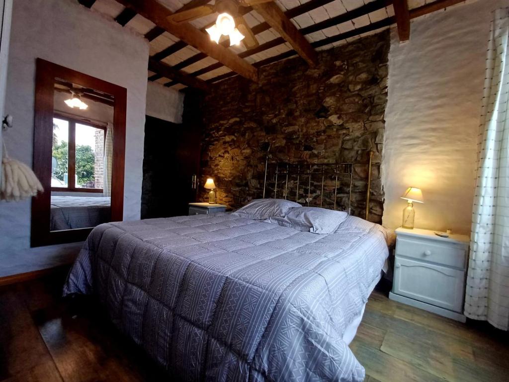 a bedroom with a bed and a stone wall at Posada San Gabriel in Colonia del Sacramento