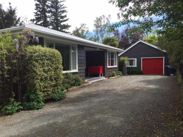una piccola casa con un garage rosso in un cortile di 28 Scarborough Tce a Hanmer Springs