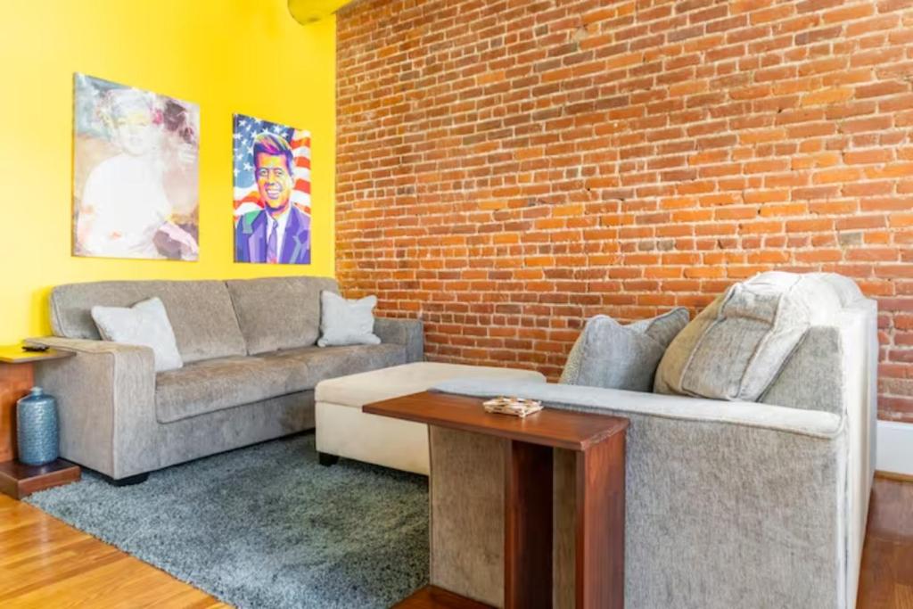 uma sala de estar com dois sofás e uma parede de tijolos em The Marilyn Monroe Loft. Central Downtown Location em Roanoke