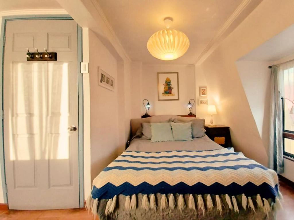 - une chambre dotée d'un lit avec une couverture bleue et blanche dans l'établissement Acogedoras y centrales habitaciones, IDEAL JUEGOS PANAMERICANOS, à Santiago