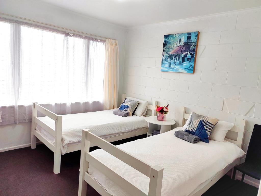 a room with three beds and a window at Nesting In Hamilton East in Hamilton