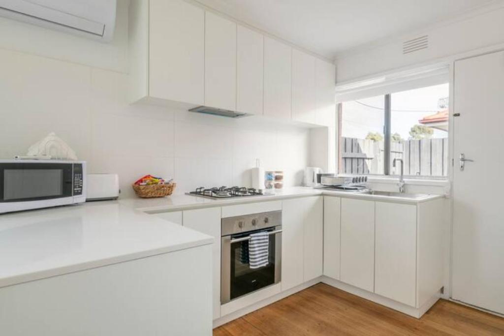 cocina blanca con armarios blancos y microondas en Quiet & Private with city access and free wifi en Melbourne