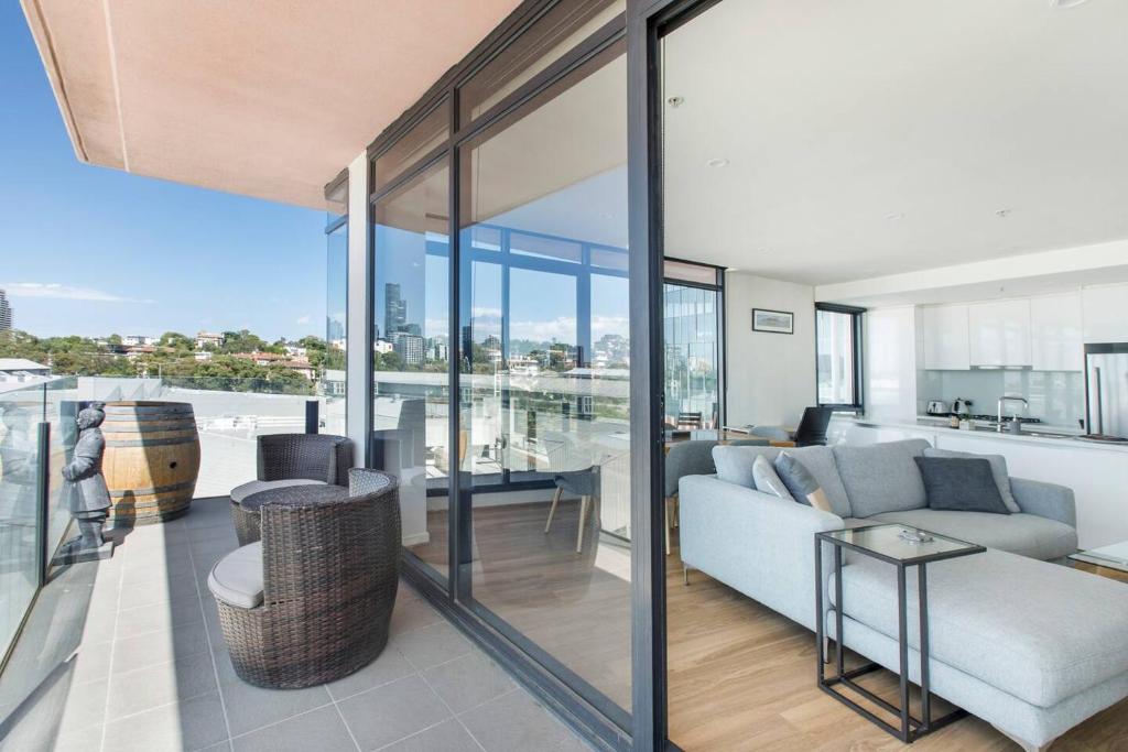 - un salon avec un canapé et des parois en verre dans l'établissement Aloft at Era with Sweeping Balcony Views, à Melbourne