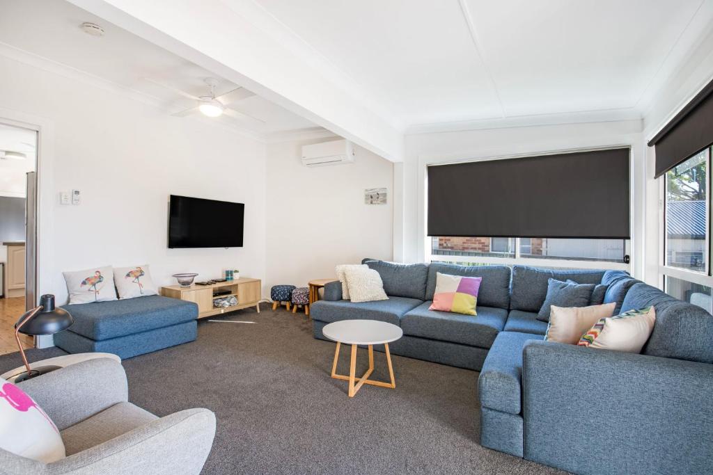 ein Wohnzimmer mit blauen Sofas und einem Flachbild-TV in der Unterkunft Tillys Retreat I Pet Friendly I 3 Min Walk to Beach in Culburra Beach