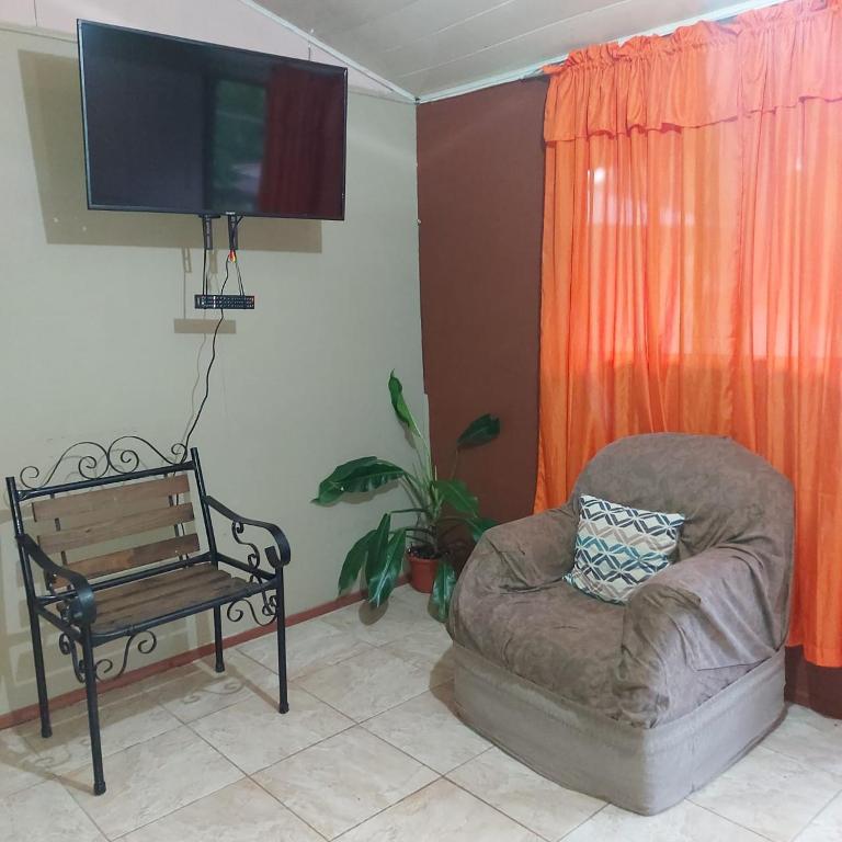 een woonkamer met een stoel en een flatscreen-tv bij Departamento Minae in Puerto Jiménez