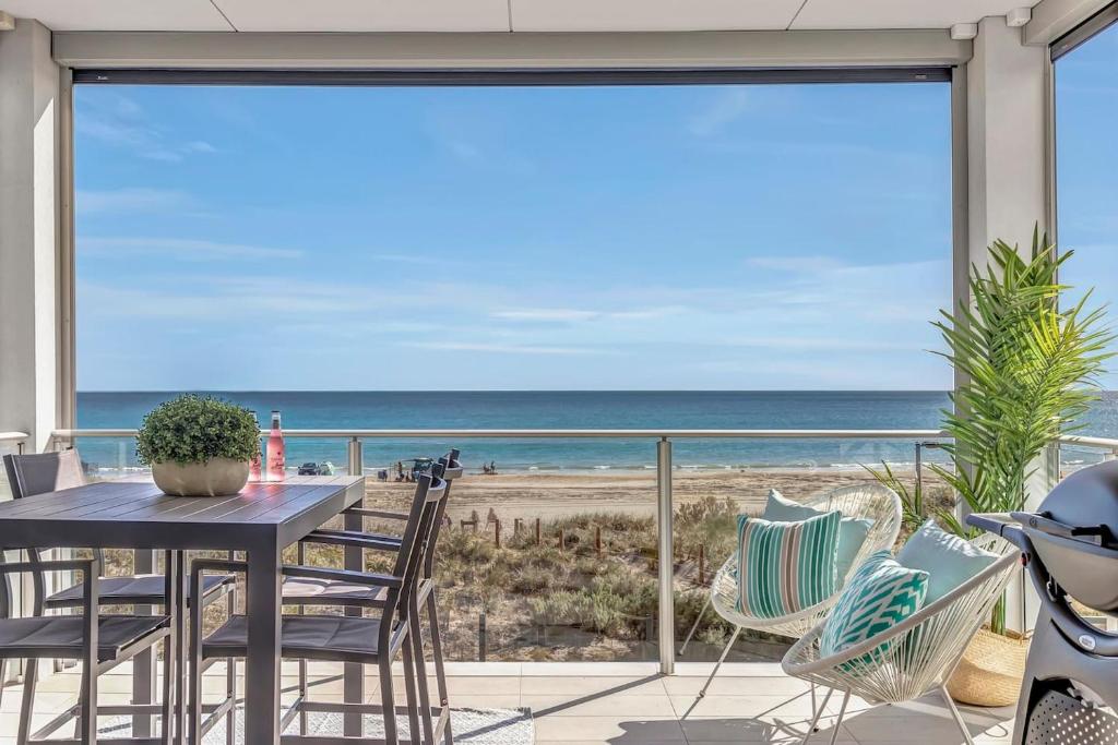 un patio con mesa y sillas y vistas a la playa en Hamptons-inspired Waterfront Living on Moana Beach, en Moana