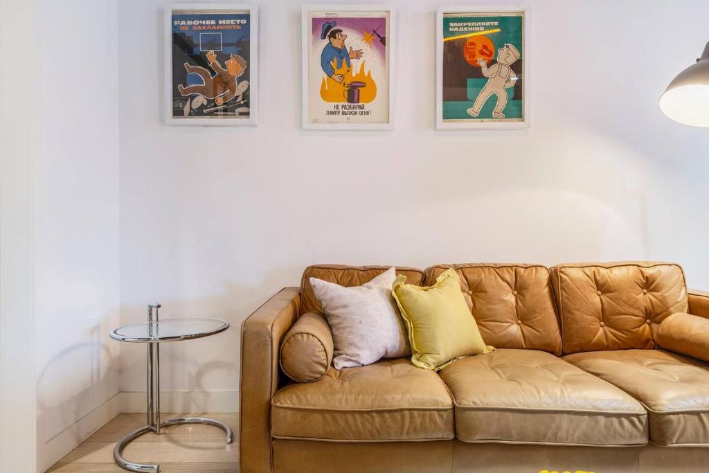 a living room with a brown couch and posters on the wall at Fitzroy Thrills in MacRobertson Factory Conversion in Melbourne