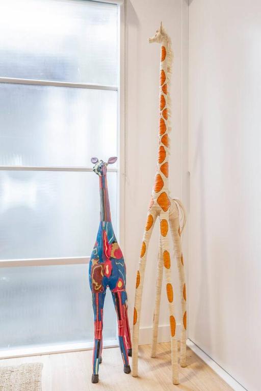 two giraffes standing next to a window in a room at Fitzroy Thrills in MacRobertson Factory Conversion in Melbourne