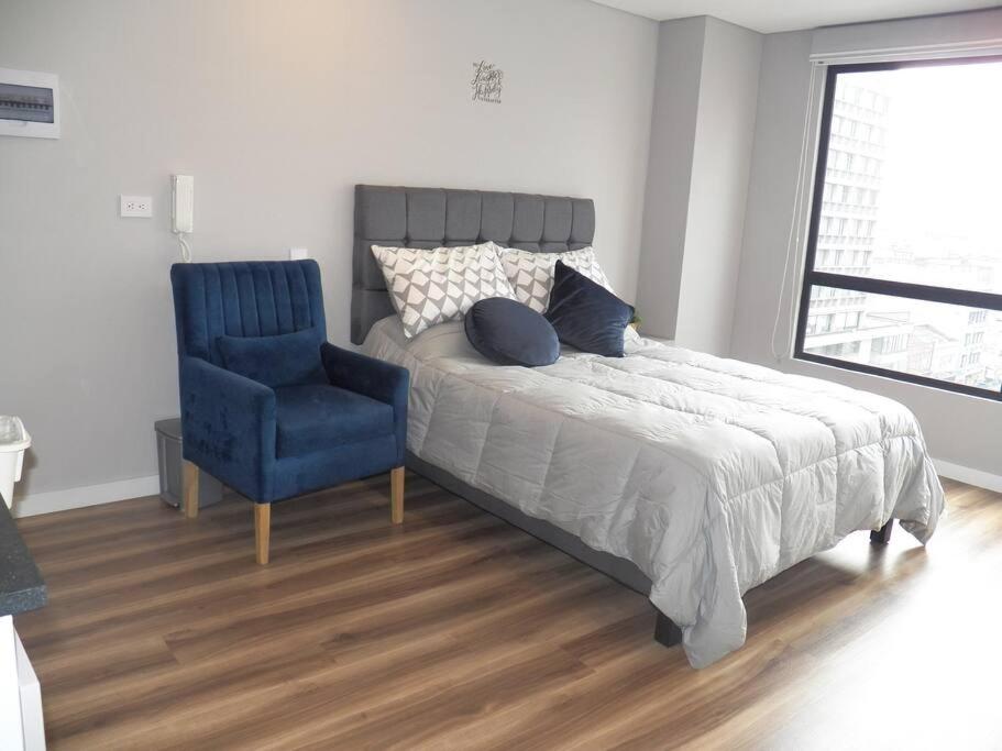een slaapkamer met een bed en een blauwe stoel bij Suite en centro histórico Bogotá in Bogota