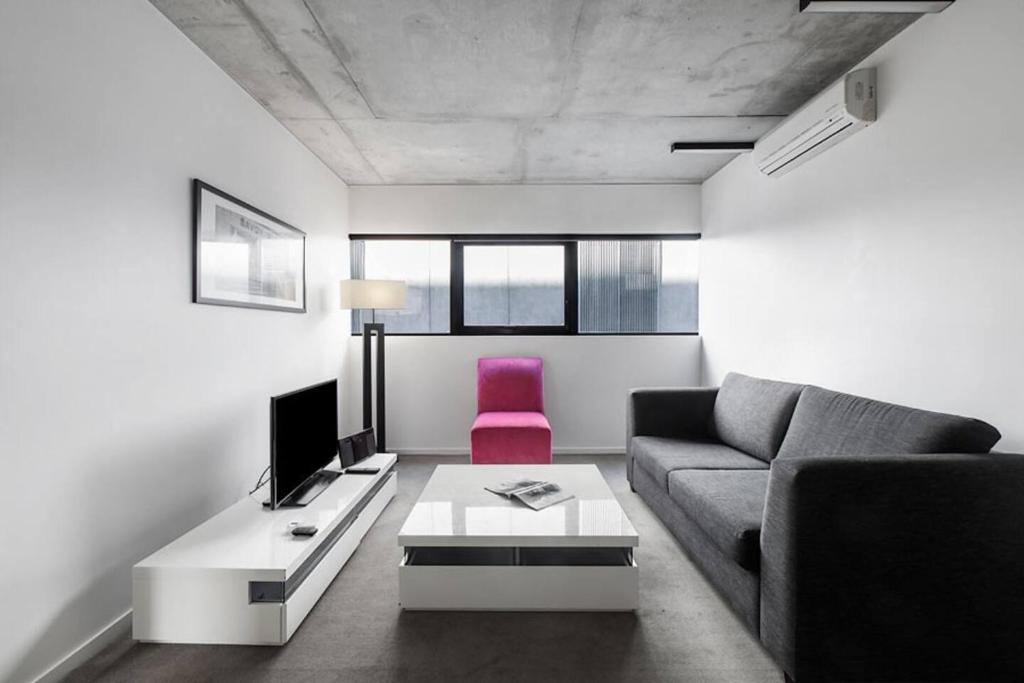 a living room with a couch and a pink chair at Refresh at Rhapsody - City-Fringe Contemporary in Melbourne