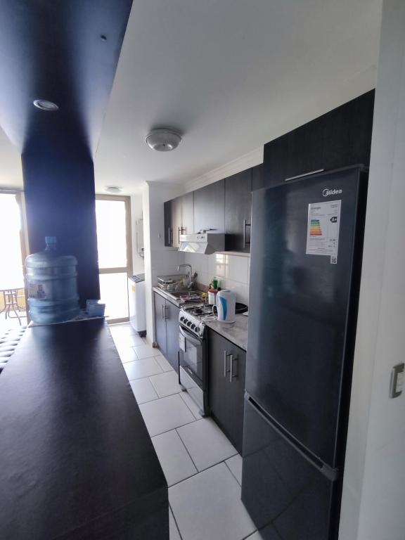 a kitchen with black cabinets and a black refrigerator at Departamento de 2 dormitorios y 1 baño in Arica