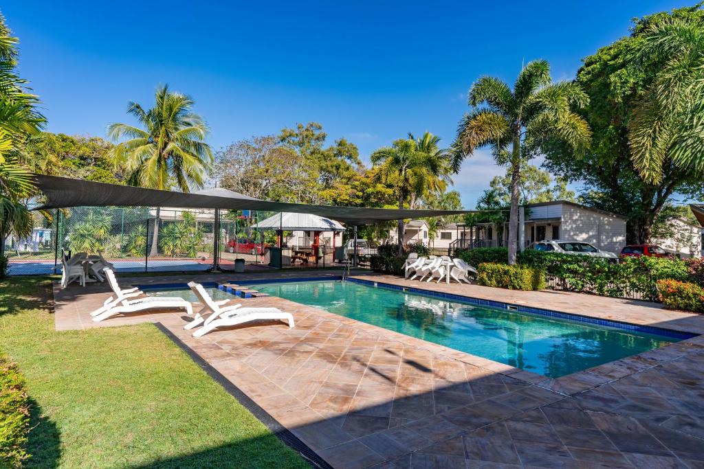 a swimming pool with two lounge chairs and a house at BIG4 Tasman Holiday Parks - Rowes Bay in Townsville