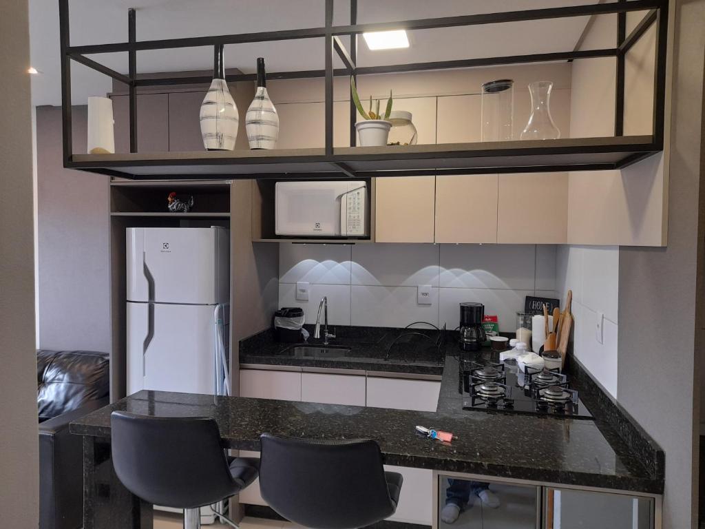 a kitchen with a black counter top and a refrigerator at Apartamento bem localizado in Bento Gonçalves