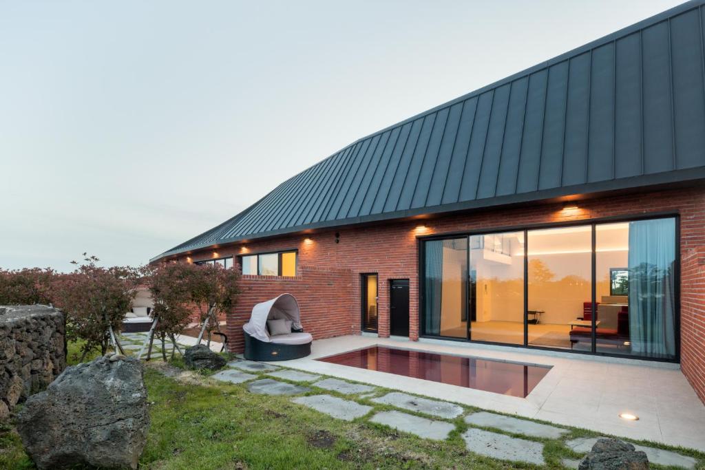 uma casa de tijolos com uma piscina em frente em Ohyeongjae Private Pool Villa em Jeju