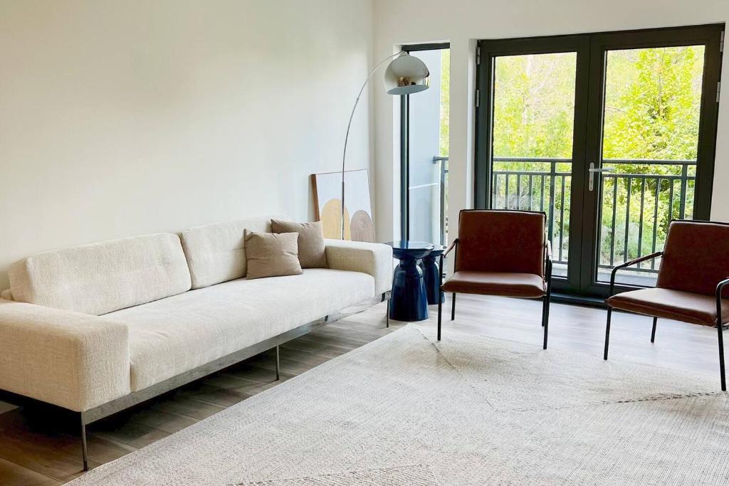 a living room with a white couch and two chairs at Modern Furnished Apartment in Heart of Quincy in Quincy