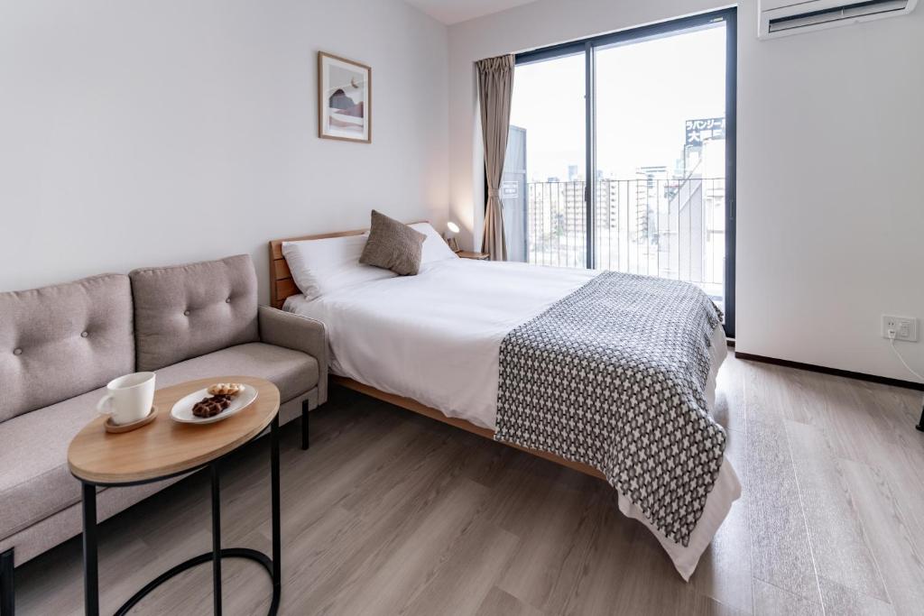 Un dormitorio con una cama, un sofá y una mesa. en SR Namba -Sanctuary Residence-, en Osaka