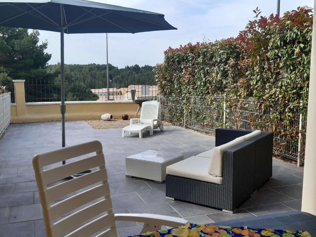 un patio avec deux chaises et un parasol dans l'établissement T2 à Narbonne-Plage, terrasse, parking, animaux admis - FR-1-409-166, à Narbonne