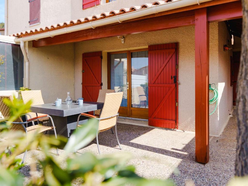 d'une terrasse avec une table, des chaises et une porte rouge. dans l'établissement Pavillon T3 rénové, proche plage, 2 chambres, terrasse, garage, WiFi - FR-1-409-170, à Narbonne