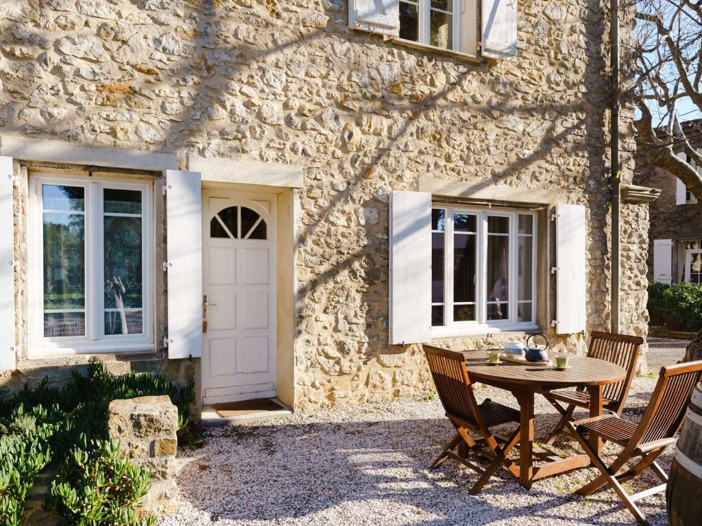 une maison en pierre avec une table et des chaises devant elle dans l'établissement Charmant gîte de 55 m² au cœur d'un domaine viticole à 2 km de Narbonne-Plage, idéal pour 5 pers. - FR-1-409-177, à Narbonne