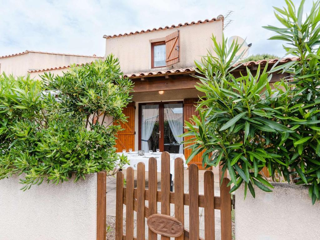 une clôture en bois devant une maison dans l'établissement Charmant Pavillon T3 avec Terrasse Sud, Piscine, Proche Mer à Gruissan - FR-1-409-198, à Gruissan