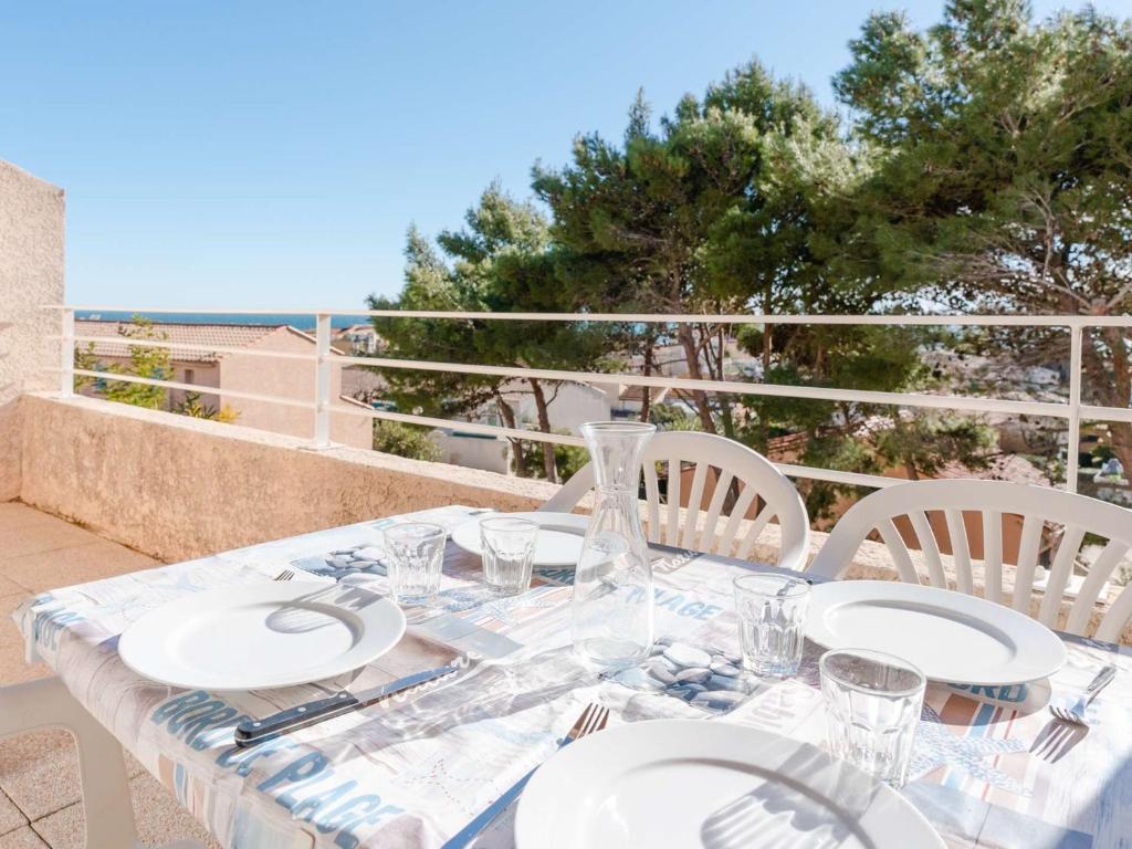 une table avec des assiettes et des verres sur un balcon dans l'établissement Duplex cosy avec piscine et WiFi, proche plage et commerces, pour 4 pers., parking inclus - FR-1-409-213, à Fleury