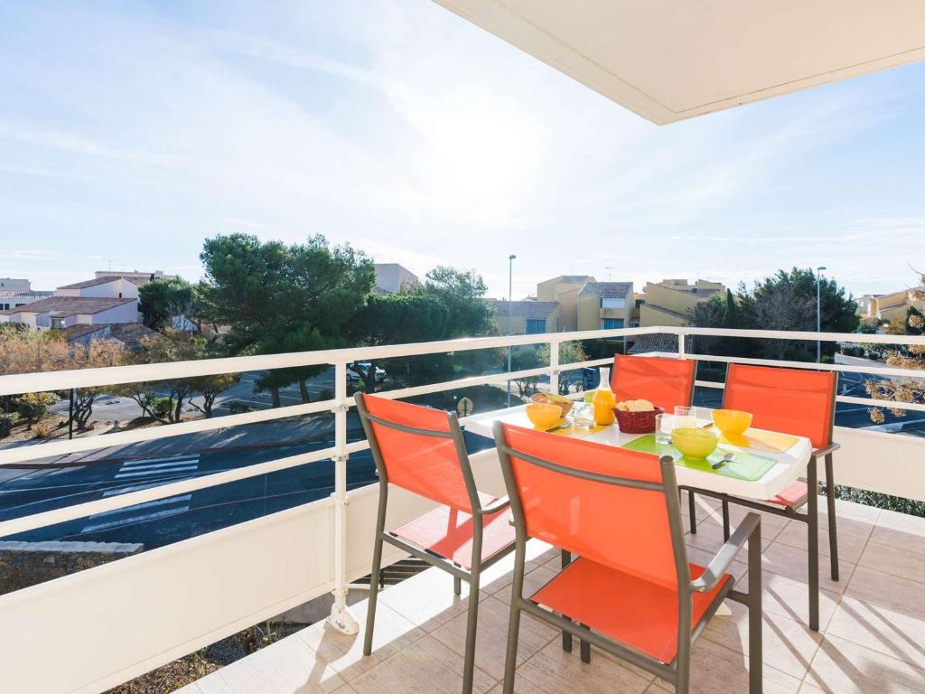 un balcon avec des chaises orange et une table avec de la nourriture. dans l'établissement Appartement moderne 3 pièces, à 300m plage, parking, WIFI, Narbonne-Plage - FR-1-409-214, à Narbonne