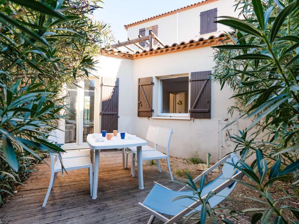 une table et des chaises sur un patio arboré dans l'établissement Charmant T2 en rez-de-jardin avec piscine, garage et WIFI à Narbonne-Plage - FR-1-409-208, à Narbonne